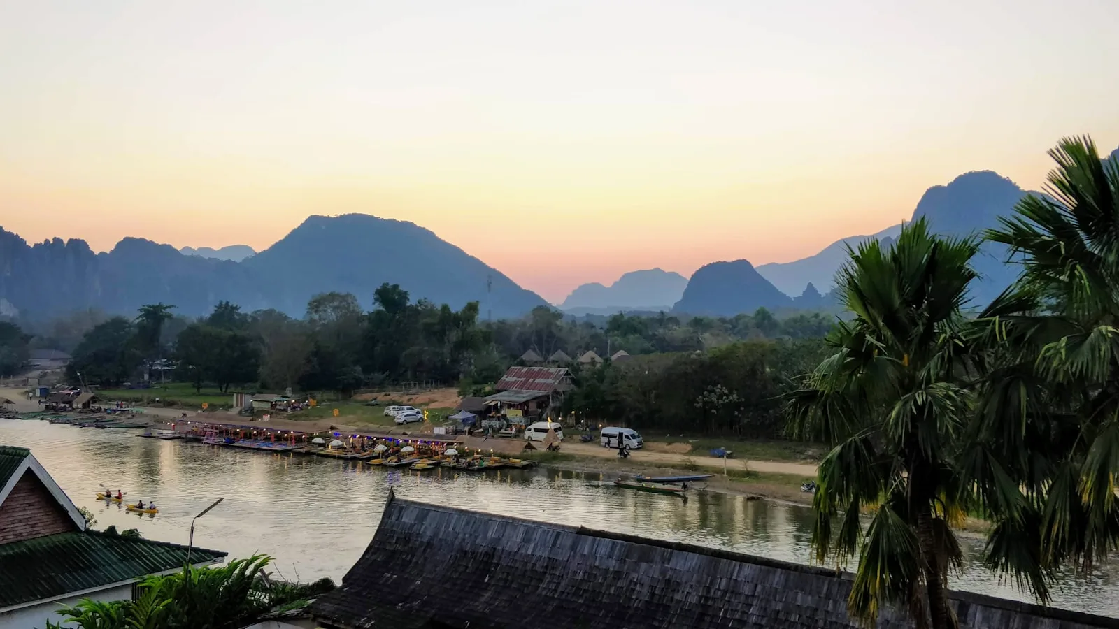 Bord du Mékong à Thakhek au coucher du soleil, avec la place coloniale et les eaux du fleuve qui reflètent le ciel doré